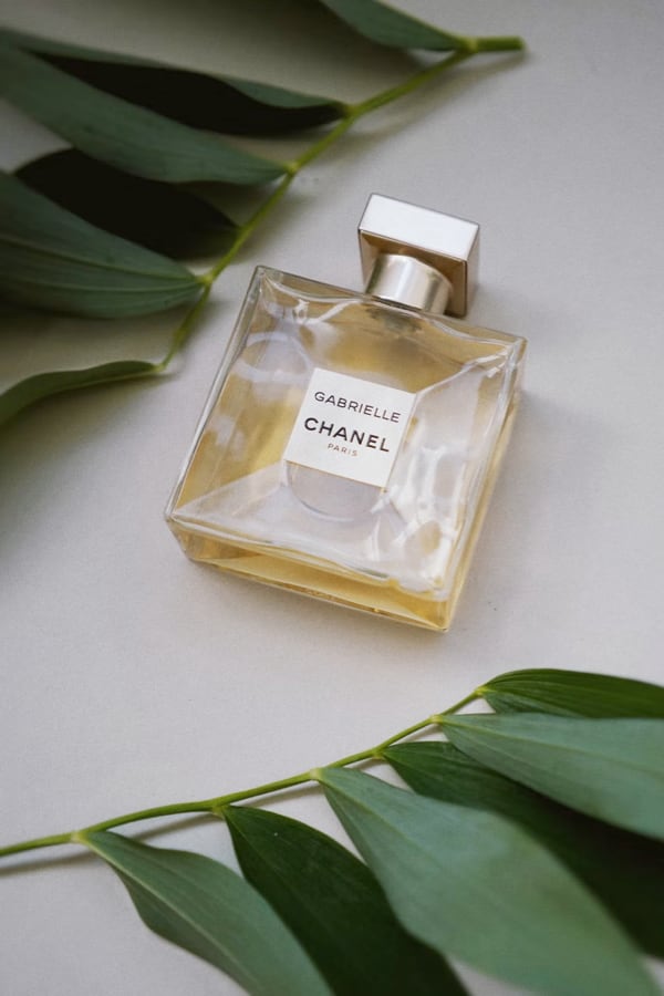 yellow perfume bottle lying on a table surrounded by leaves